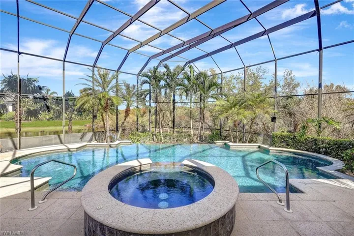 View of pool featuring glass enclosure and an in ground hot tub