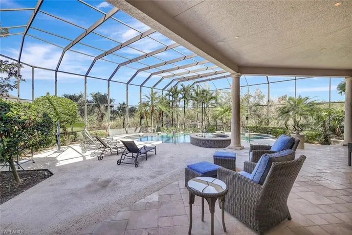 View of patio with glass enclosure and a swimming pool with hot tub