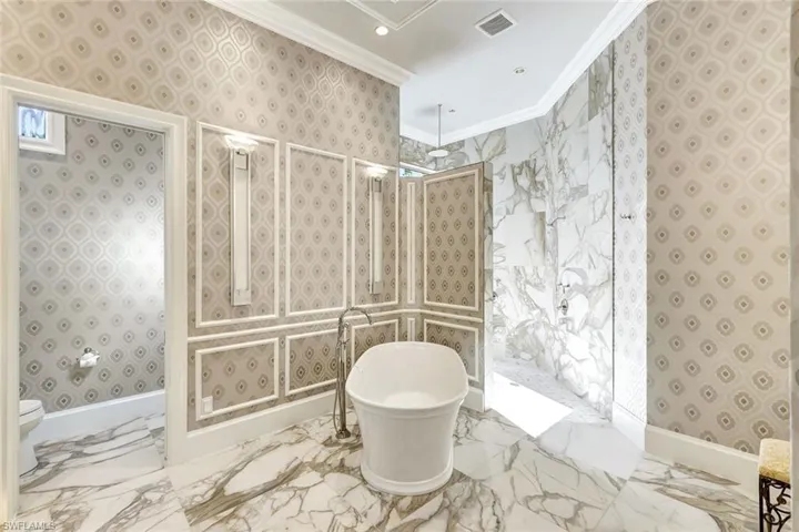 Bathroom with crown molding and independent shower and bath
