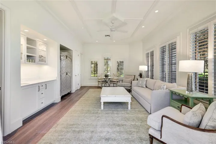 Living room featuring ceiling fan, crown molding, and dark wood-type flooring
