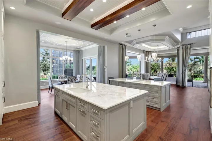Kitchen featuring sink, dark hardwood / wood-style floors, a notable chandelier, and an island with sink