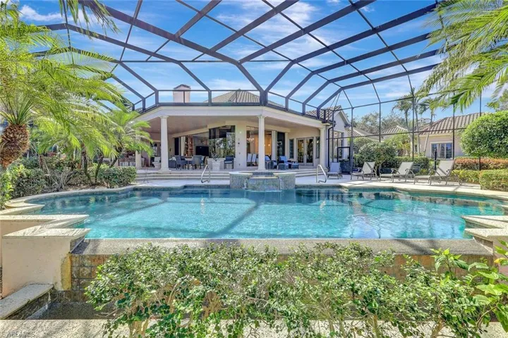 View of pool with glass enclosure, a patio area, and an in ground hot tub