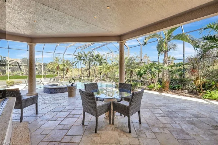 View of patio / terrace featuring glass enclosure and an in ground hot tub
