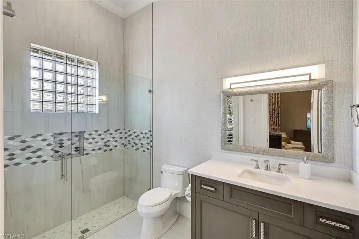 Bathroom featuring an enclosed shower, vanity, and toilet