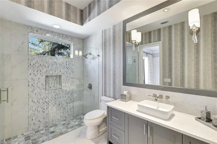 Bathroom featuring vanity, a shower with shower door, and toilet