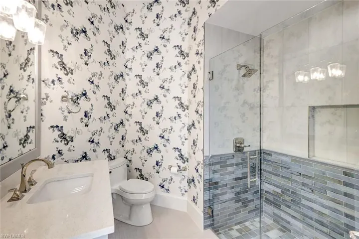 Bathroom with vanity, toilet, tile walls, and a shower with shower door