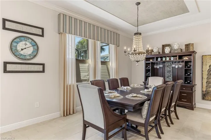 Formal dining space featuring a coffered ceiling with a chandelier, large windows with valance and drapes, and a built-in dark wood hutch