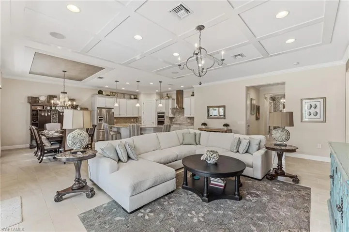 Open-concept living space featuring a coffered ceiling with recessed lighting and a decorative chandelier
