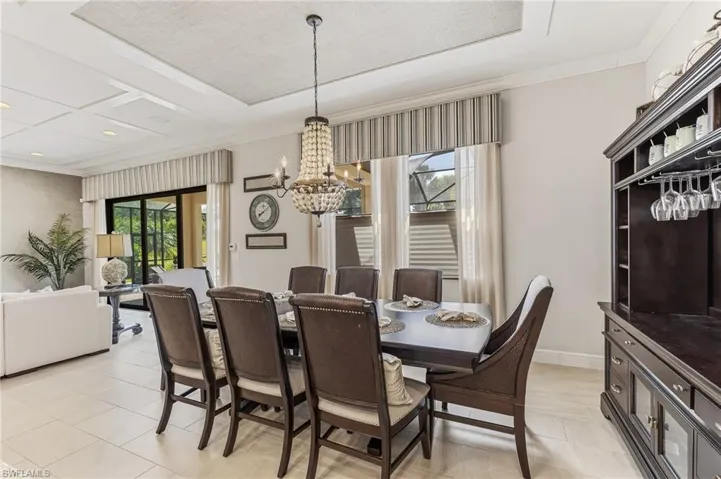 Formal dining space featuring a chandelier light fixture, recessed ceiling detail, and large format tile flooring