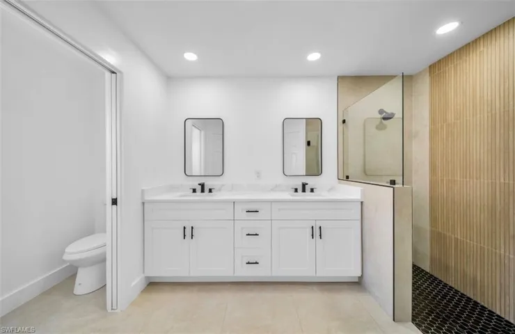 Bathroom with walk in shower, double vanity, recessed lighting, and light tile patterned floors