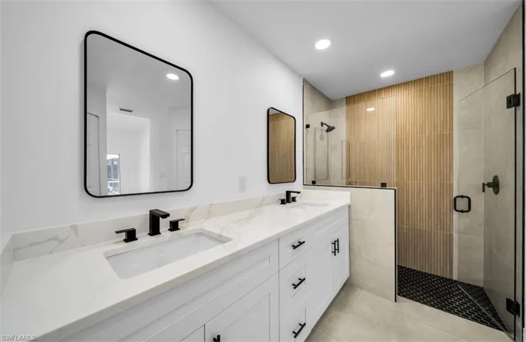 Bathroom with double vanity, a stall shower, recessed lighting, and light tile patterned floors
