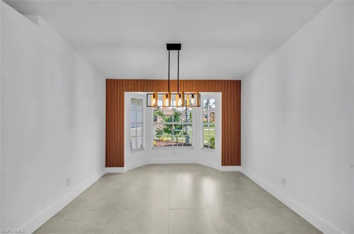 Unfurnished dining area with a chandelier and light tile patterned floors