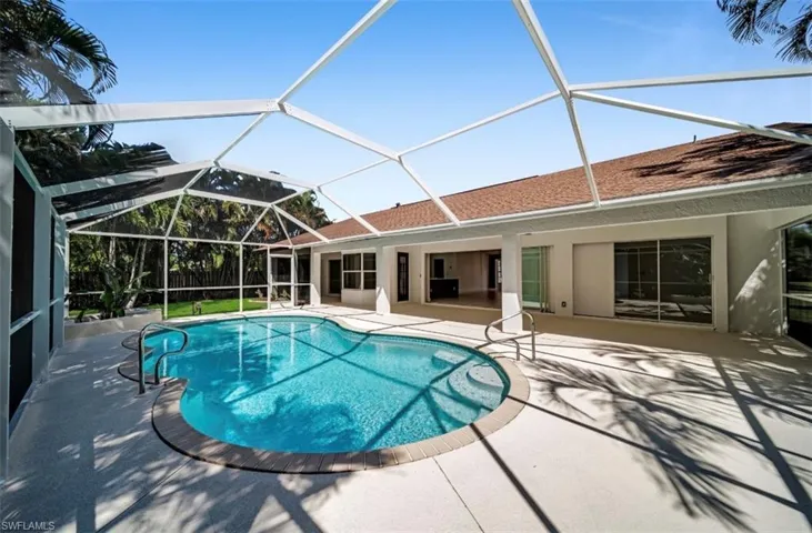 Outdoor pool featuring a sunroom, glass enclosure, and a patio area