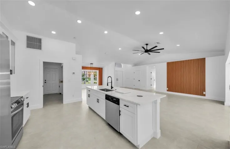 Kitchen with white cabinets, an island with sink, light stone counters, stainless steel appliances, and recessed lighting