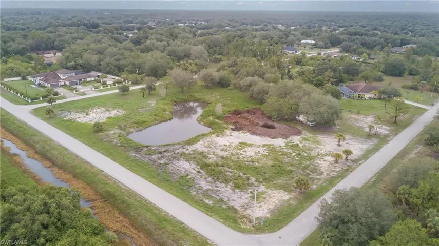 Aerial view of property's location with a nearby body of water and a heavily wooded area