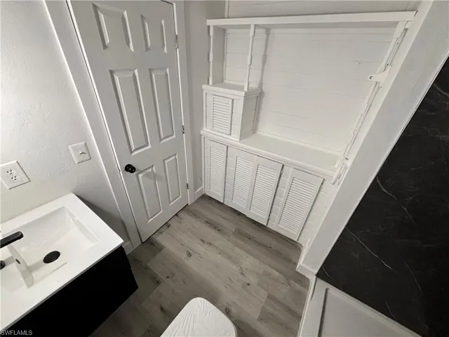 Full bath with vanity and dark wood-type flooring
