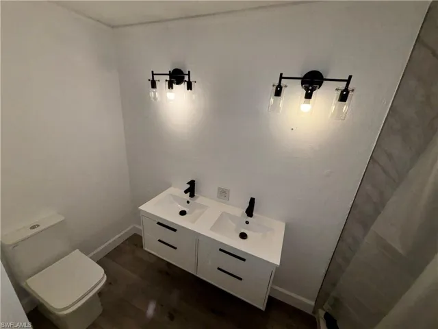 Bathroom featuring double vanity and dark wood-style floors
