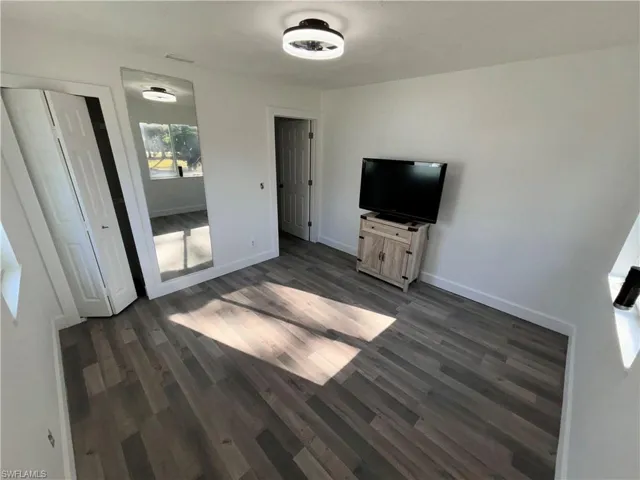 Unfurnished bedroom with dark wood-style floors and a closet