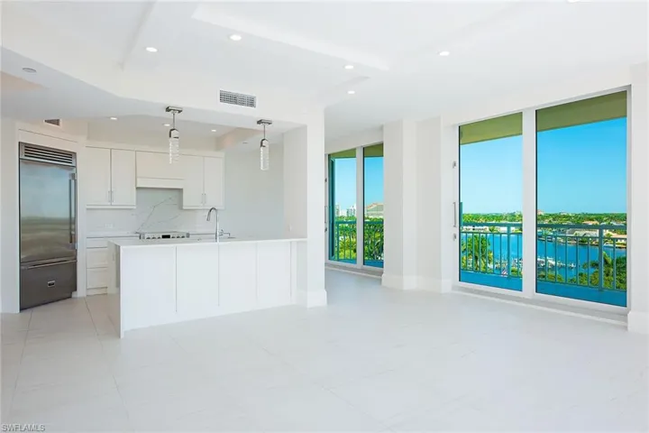 Kitchen featuring decorative light fixtures, recessed lighting, white cabinetry, stainless steel built in refrigerator, and tasteful backsplash