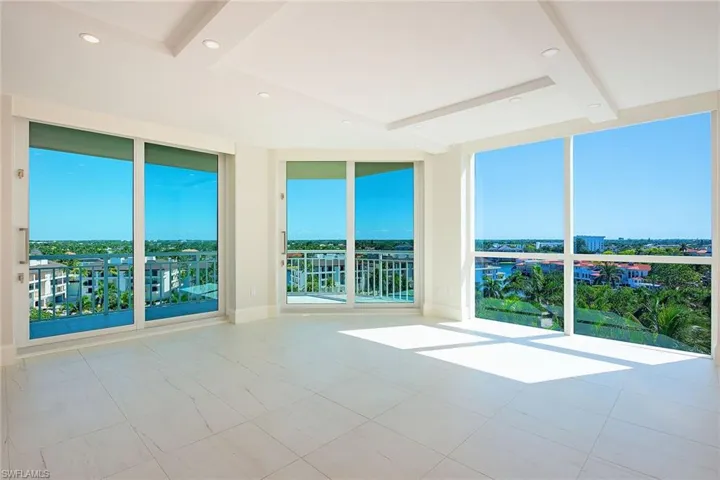 Unfurnished room with expansive windows, plenty of natural light, recessed lighting, and beam ceiling