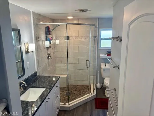 Bathroom with hardwood / wood-style floors, vanity, and an enclosed shower