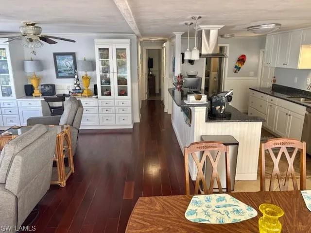 Kitchen featuring white cabinets, dark hardwood / wood-style flooring, sink, and hanging light fixtures