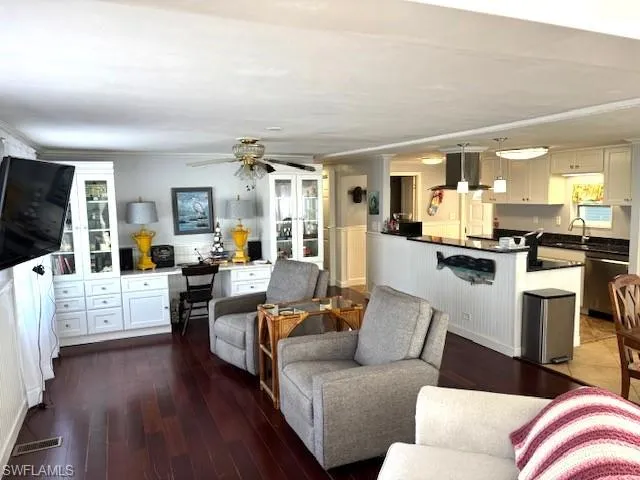 Living room with dark hardwood / wood-style floors, ceiling fan, crown molding, and sink