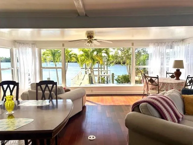 Sunroom / solarium with beam ceiling, ceiling fan, and a water view
