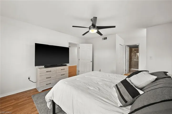 Bedroom featuring hardwood / wood-style floors, connected bathroom, and ceiling fan