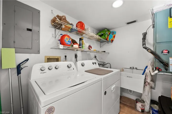 Washroom with sink, electric panel, independent washer and dryer, and light tile patterned floors