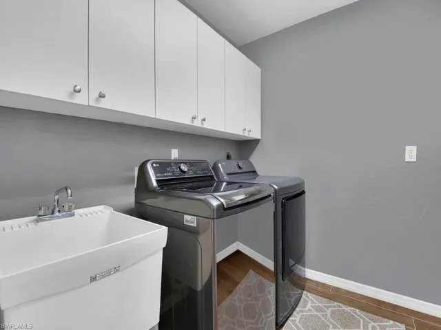 Laundry room featuring washing machine and dryer, cabinet space, and wood finished floors
