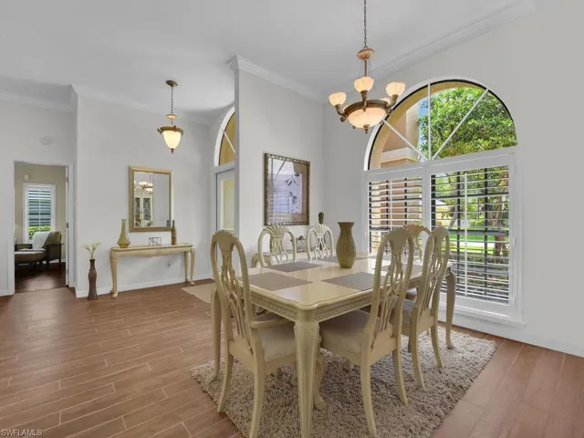 Dining area featuring crown molding, wood finished floors, a chandelier, and a towering ceiling