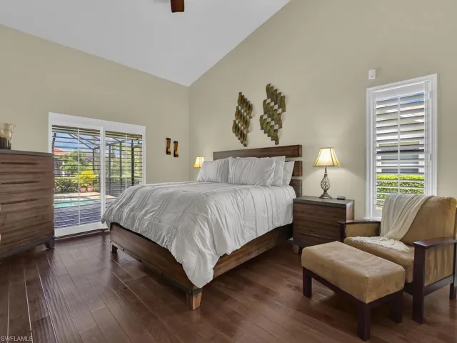 Bedroom with access to exterior, dark wood finished floors, high vaulted ceiling, and a ceiling fan