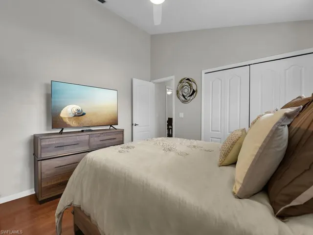 Bedroom with dark wood-type flooring, a closet, vaulted ceiling, and a ceiling fan