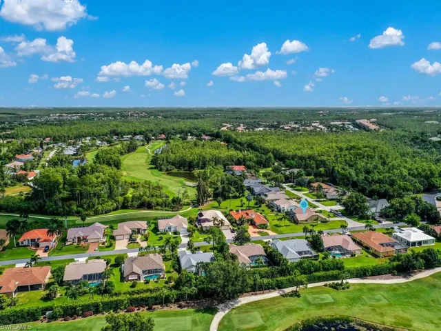 Aerial view of residential area featuring a golf course and a large body of water