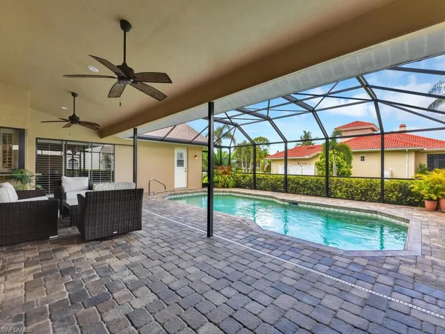 Swimming pool with ceiling fan, glass enclosure, a patio, and an outdoor living space