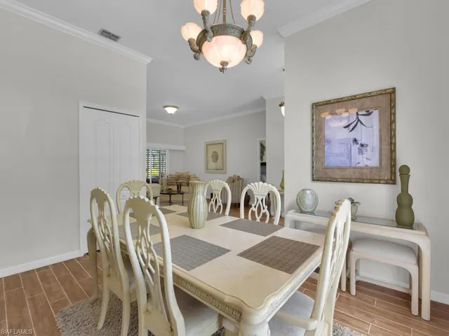 Dining space with wood tiled floors, a chandelier, and ornamental molding