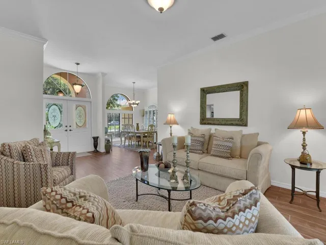 Living area featuring ornamental molding, wood finished floors, and a chandelier