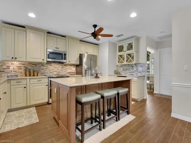 Kitchen with a ceiling fan, tasteful backsplash, cream cabinetry, stainless steel appliances, and a breakfast bar