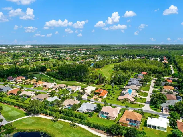 Aerial view of property's location featuring a golf course and nearby suburban area