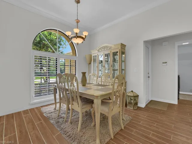 Dining space featuring wood finish floors, crown molding, and a chandelier