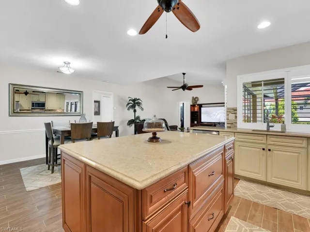 Kitchen with brown cabinetry, decorative backsplash, wood finish floors, a center island, and recessed lighting