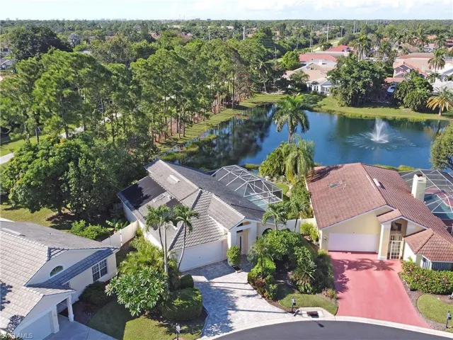Aerial view of residential area with a nearby body of water and a tree filled landscape