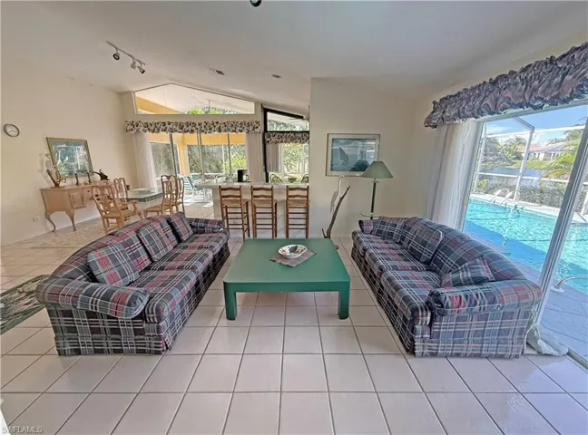Tiled living room featuring vaulted ceiling, healthy amount of natural light, and a sunroom