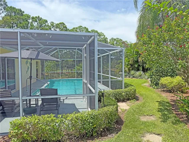 Swimming pool with a patio area, glass enclosure, view of scattered trees, and a sunroom