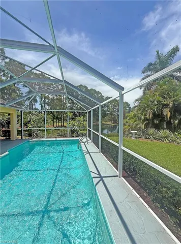 Outdoor pool with a sunroom, a yard, a lanai, and a water view