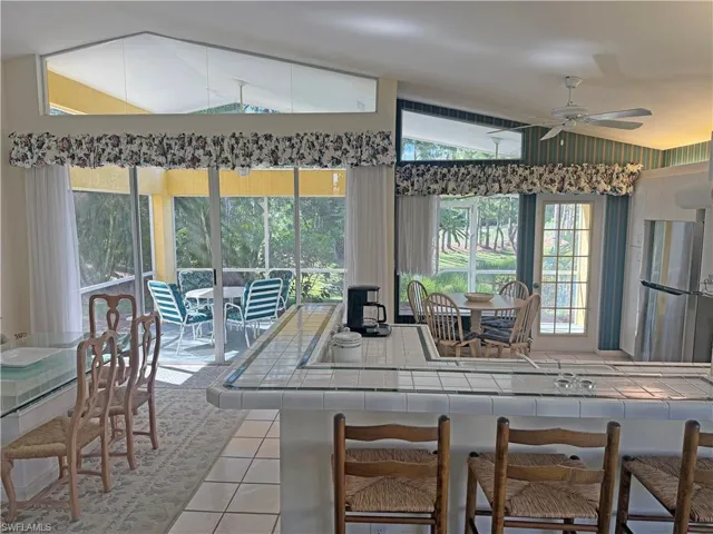 Kitchen with light tile patterned floors, ceiling fan, vaulted ceiling, and tile counters
