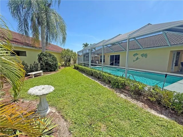 View of grassy yard featuring an outdoor pool, a sunroom, and glass enclosure