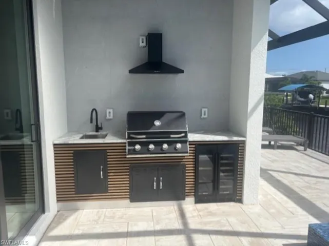 View of patio featuring exterior kitchen and a sink