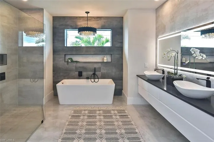 Full bath featuring a freestanding tub, double vanity, a walk in shower, and tile walls
